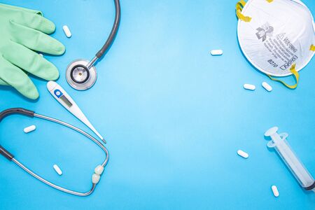 Concept of Coronavirus or Covid-19 pandemic to use as background with blue colour and medical blood test, stethoscope, mask, thermometer, gloves, syringe, pill tablet medicinesの写真素材