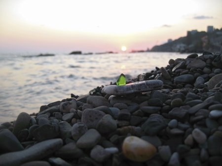 Green glass laying on the sea shoreの写真素材