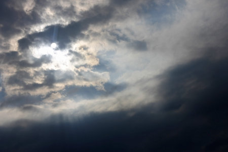Blue sky and heavy clouds and the sun behind