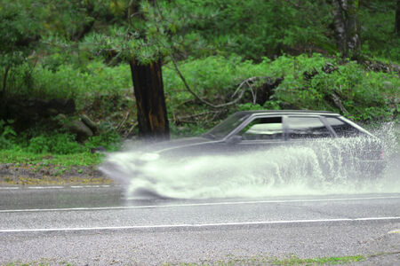 Automobile driving on the puddle on a highwayの写真素材