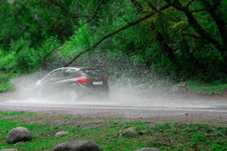 Automobile driving on the puddle on a highwayの写真素材