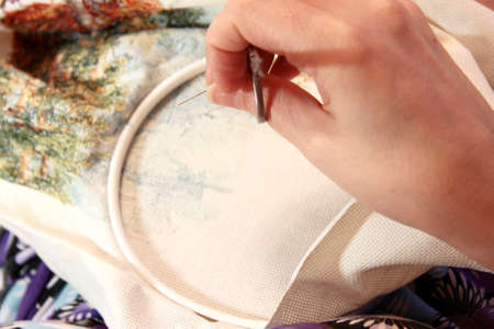 Woman sewing decoration picture on the white fabricの写真素材