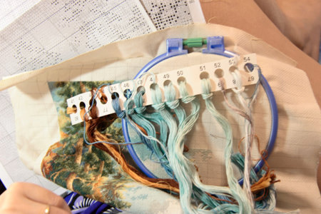 Woman sewing decoration picture on the white fabric