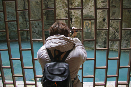 Adult Female with black bagpack making movie by camcorder inside Mashuk mountain, Proval lake, Pyatigorsk, Russian Federationの写真素材