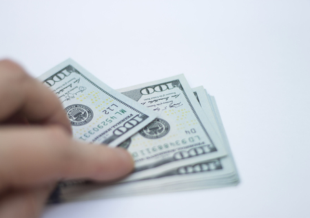 Mans Fingers Holding A Stack Of new 100 Paper Dollars Usa isolated and blured On The White Backgroundの写真素材