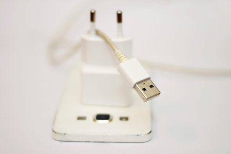 Modern white smartphone and phone charge with power cord isolated on the white bckground