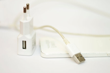 Modern white smartphone and phone charge with power cord isolated on the white bckground