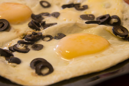 Morning roasted whole eggs on the black plate and with black olives closeup