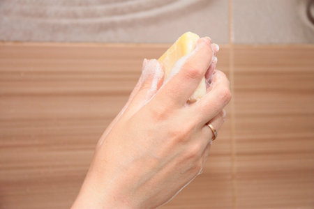 Woman cleaning her hands by sponge in bath in the bathroom