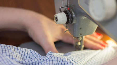 Woman taylor is working on the sewing machine closeupの写真素材