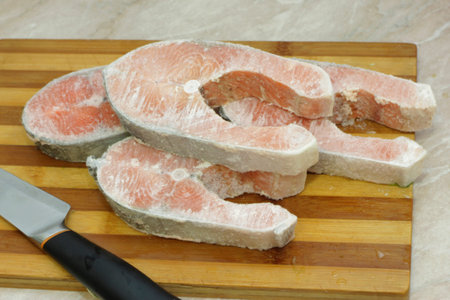 Frozen salmon raw red fish steak on the cooking table in the kitchen
