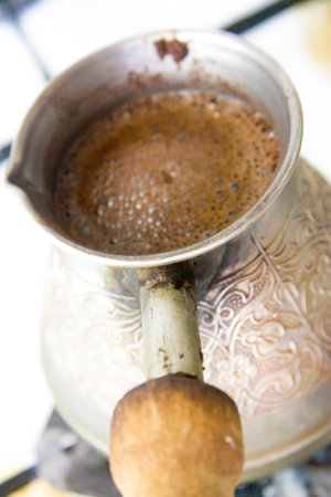 Blured hot tasty coffee traditionally prepearing in old turk on hot cooking stove closeupの写真素材