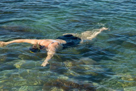 Adult woman diving into clear water of sea near a shoreの写真素材