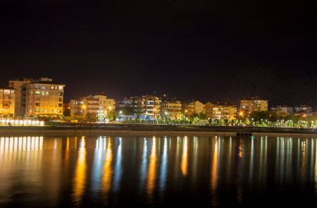 View of the illuminated night town line in Antalya Konyalti Turkey and river reflection at night timeの写真素材