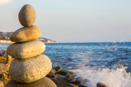 Balanced stones on the seashore summertime and splashing sea waves backgroundの写真素材