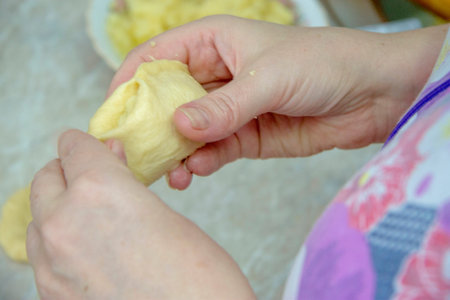 Woman stuffs homemade pies with potatoes and onion in the kitchen closeup