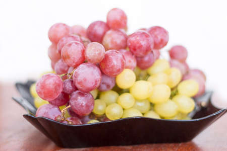 Red and White wine bunch of grapes in the black plate ready to eatの写真素材