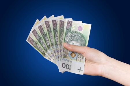 Hand with polish money on blue backgroundの写真素材