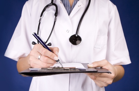Healthcare professional, doctor or nurse, writing with a fountain pen on a paper over a folder.の写真素材