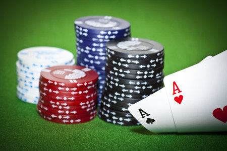 Gambling chips, ace of diamonds and king of spades on green poker cloth.
