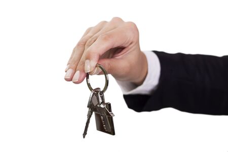 Woman holding out house keys on a silver house-shaped keychainの写真素材