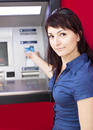 Beautiful woman using credit card, she is withdrawing money from an ATM machine の写真素材