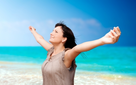 Beautiful young woman with arms raised standing on beachの写真素材