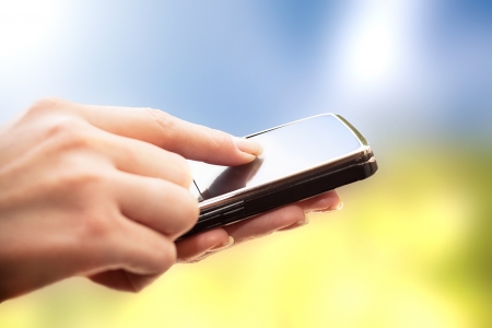 Closeup of female hands using a smart phone  Nature background の写真素材