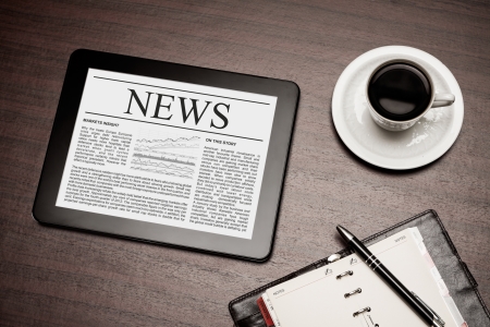 Tablet PC shows latest news on screen, which lying on work place  の写真素材