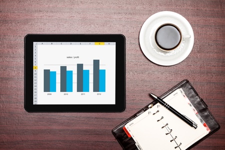 Modern workplace with digital tablet showing charts and diagram on screenの写真素材