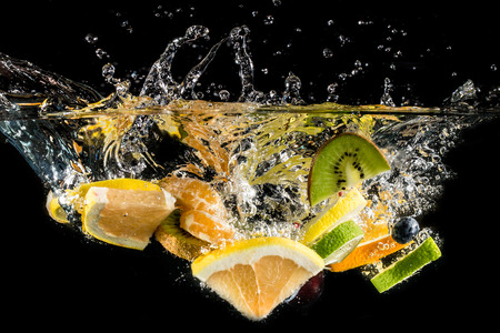 Splashing fresh fruit on water isolated on black の写真素材