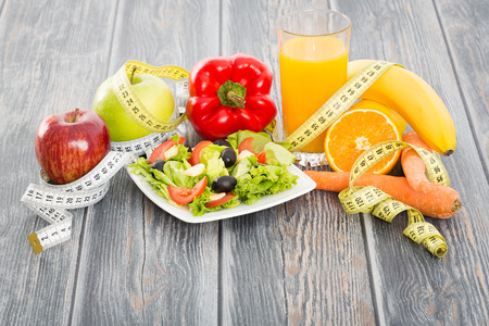 Fitness salad and measuring tape on rustic wooden table.の写真素材