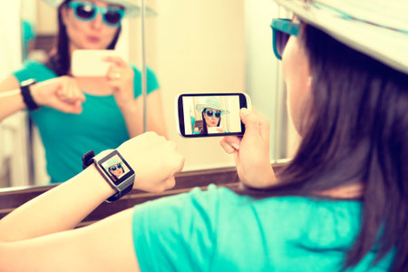 Woman taking self portrait selfie photo and sends it to smartwatch.