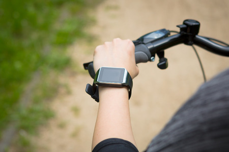 Woman riding a bike with a SmartWatch heart rate monitor. Smart watch concept.の写真素材