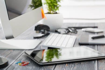 Office workplace with tablet and pc on wood table.