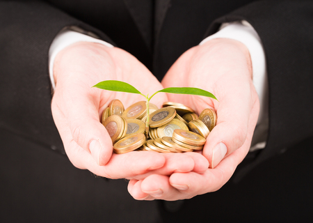 Businessman cover growing plant with coin money.の写真素材