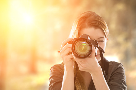Portrait of a photographer covering her face with the camera.の写真素材