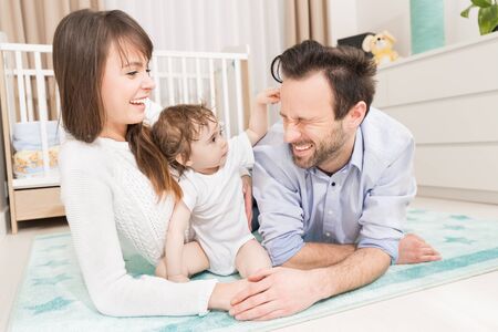 Happy parents playing with your baby. Joyful family main subject. Mom and dad laughs at her daughter.の写真素材