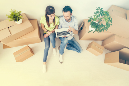 A young couple sitting in a new apartment and uses a laptop. Discuss home repair projects while moving.の写真素材