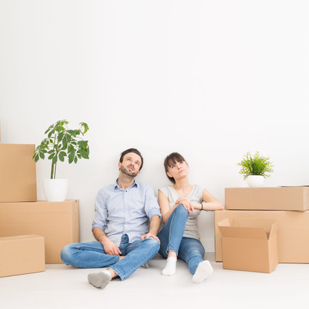 A young couple sitting on the floor and looking up. Dream and enjoy your new home.