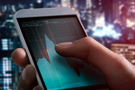 trader broker forex investment hold smartphone stock market chart screenの写真素材