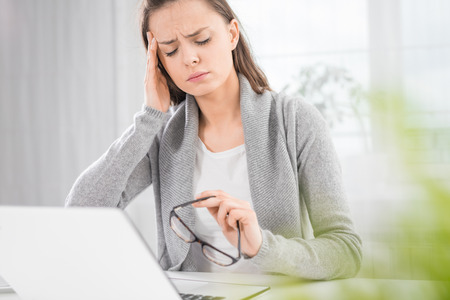 Young woman is tired and feels stressed out. Frustrated, she closed eyes and massage temples head.