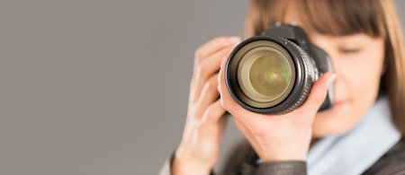 Portrait of a photographer covering her face with the camera.の写真素材