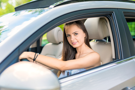 Beautiful young woman sitting in the interior of a new car with a smile. He is glad he is a driver.の写真素材