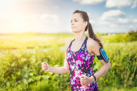 Beautiful, young woman running on the water's edge by the country road. Jogging concept.の写真素材