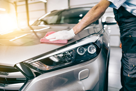 Car detailing - the man holds the microfiber in hand and polishes the car. Selective focus.の写真素材