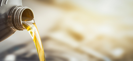 Pouring oil to car engine. Fresh oil poured during an oil change to a car.の写真素材
