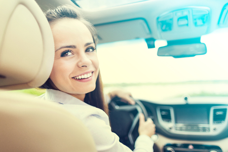 Beautiful young woman sitting in the interior of a new car with a smile. He is glad he is a driver.の写真素材
