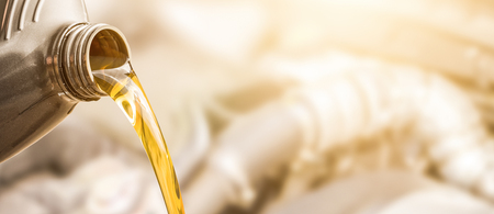 Pouring oil to car engine. Fresh oil poured during an oil change to a car.の写真素材