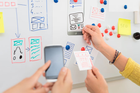 A group of people designers designing a wireframe application of mobile phone and responsive...